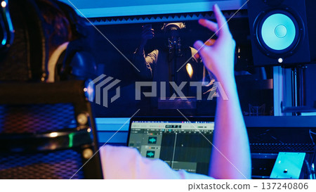 Audio Engineer Adjusts Sound On Laptop, Musician Records Vocal. Creative Collaboration, Modern Music Production, Inspiration At Night Studio. Audio Engineer Adjusts Sound On Laptop, Musician Records Vocal. Creative Collaboration, Modern Music Production, Inspiration At Night Studio. 137240806