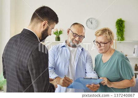 Real estate agent helping mature senior couple sign contract during home visit Real estate agent helping mature senior couple sign contract during home visit 137240867