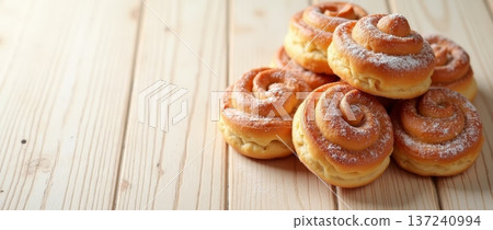 Fresh pastries cinnamon rolls sit on wooden surface waiting to be enjoyed at breakfast time in a bakery with bright light 137240994