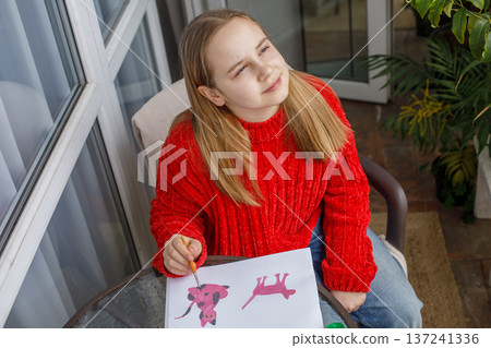 Joyful child drawing pink cats in a sketchbook. Young preteen girl painting Joyful child drawing pink cats in a sketchbook. Young preteen girl painting 137241336