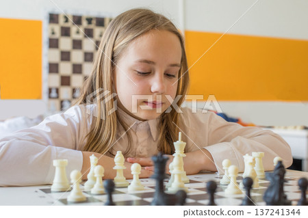 Attractive child school student on chess lesson indoor. Young girl 10 years old playing chess Attractive child school student on chess lesson indoor. Young girl 10 years old playing chess 137241344