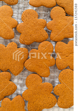 Freshly baked Orange Zest Gingerbread Cookies in gingerbread girl shapes cooling on a wire rack, viewed from an angled perspective. Freshly baked Orange Zest Gingerbread Cookies in gingerbread girl shapes cooling on a wire rack, viewed from an angled perspective. 137241569