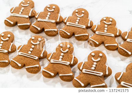 A collection of decorated gingerbread men cookies lined up neatly, highlighting their detailed royal icing designs and holiday charm. 137241575
