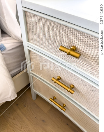 Close up view of dresser drawers featuring textured panels and gold metal handles. The elegant design combines light neutral tones with metallic accents under soft indoor lighting. The style feels Close up view of dresser drawers featuring textured panels and gold metal handles. The elegant design combines light neutral tones with metallic accents under soft indoor lighting. The style feels 137241620