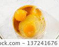 Close overhead view of eggs and liquid ingredients mixed lightly in a glass bowl. Bright lighting emphasizes color contrast and clean baking environment. 137241676