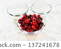 An image of fresh cranberries in a glass bowl, paired with sugar and other ingredients, ideal for cranberry dishes or holiday recipes. 137241678