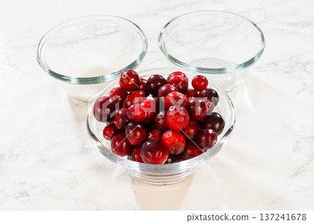 An image of fresh cranberries in a glass bowl, paired with sugar and other ingredients, ideal for cranberry dishes or holiday recipes. An image of fresh cranberries in a glass bowl, paired with sugar and other ingredients, ideal for cranberry dishes or holiday recipes. 137241678