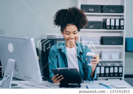 Young African American black woman working on laptop and mobile phone Young African American black woman working on laptop and mobile phone 137241853
