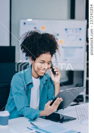 Young African American black woman working on laptop and mobile phone Young African American black woman working on laptop and mobile phone 137241854