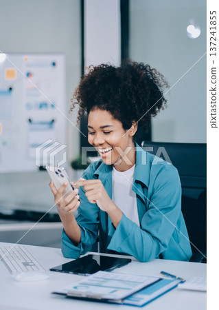 Young African American black woman working on laptop and mobile phone Young African American black woman working on laptop and mobile phone 137241855