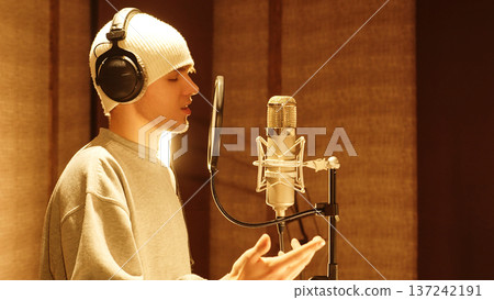 Young Musician Gestures Emotionally Singing Into Microphone. Studio Showcases Creative Performance, Modern Music Production, Talent Expression. 137242191