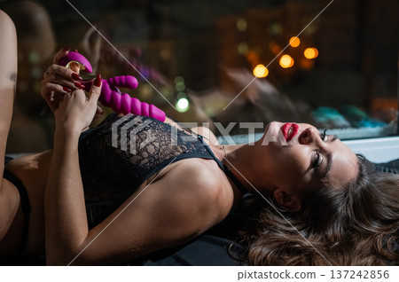 Beautiful brunette in lace lingerie holds pink dildo.  137242856