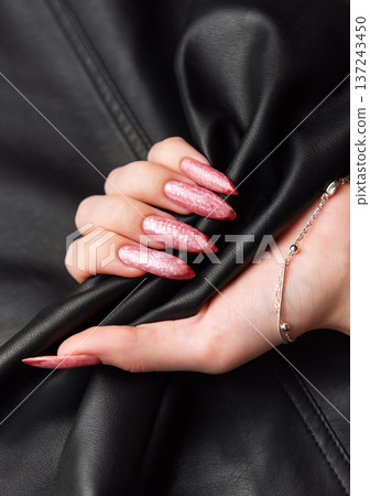 Woman hand with long acrylic pink nails holding leather 137243450