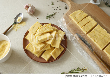 Sliced pieces of hard polenta on table. Cornmeal in kitchen. Ingredients and traditional Italian cuisine. Sliced pieces of hard polenta on table. Cornmeal in kitchen. Ingredients and traditional Italian cuisine. 137246236