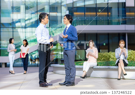 Male and female business people chatting in the office lobby Male and female business people chatting in the office lobby 137246522