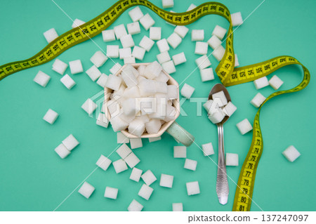 Cup filled with sugar cubes and measuring tape 137247097