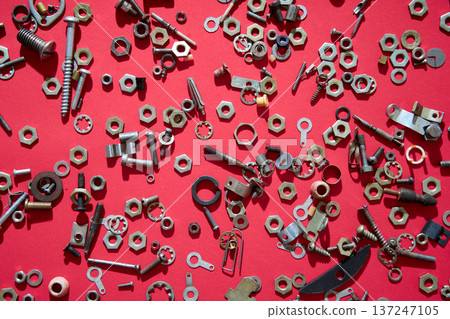 Metal nuts and bolts on red background 137247105