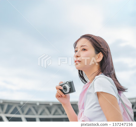 一名女子手持相機，仰望天空。照片由關西國際機場（KIX）提供。 137247156