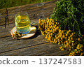 Tansy infusion in a glass on a wooden table. Tansy is a medicinal plant used in folk medicine. 137247583