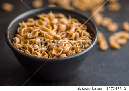 Wholegrain conchiglie pasta in bowl on black table. 137247840