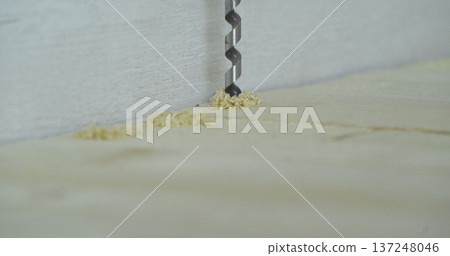 Drill is making holes in wood during a project at a workspace in the afternoon 137248046