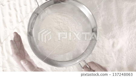 Sifting flour in a kitchen for baking bread and other dishes during the afternoon Sifting flour in a kitchen for baking bread and other dishes during the afternoon 137248063