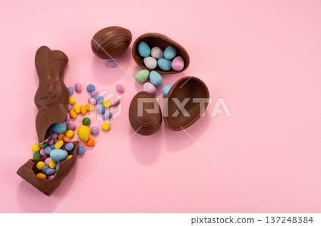 Chocolate Easter eggs and colorful sweets on a pink background. Chocolate Easter eggs and colorful sweets on a pink background. 137248384