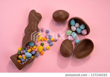 Chocolate Easter eggs and colorful sweets on a pink background. Chocolate Easter eggs and colorful sweets on a pink background. 137248385