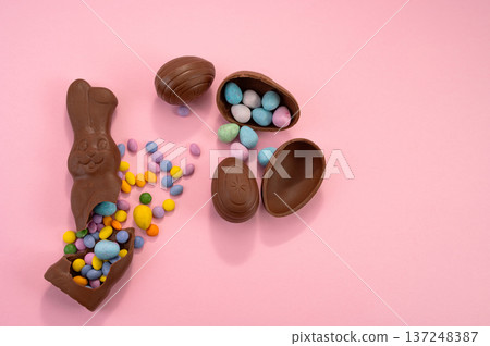 Chocolate Easter eggs and colorful sweets on a pink background. Chocolate Easter eggs and colorful sweets on a pink background. 137248387