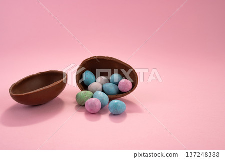 Chocolate Easter eggs and colorful sweets on a pink background. Chocolate Easter eggs and colorful sweets on a pink background. 137248388