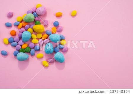 Chocolate Easter eggs and colorful sweets on a pink background. Chocolate Easter eggs and colorful sweets on a pink background. 137248394