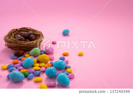 Chocolate Easter eggs and colorful sweets on a pink background. Chocolate Easter eggs and colorful sweets on a pink background. 137248399