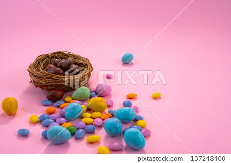 Chocolate Easter eggs and colorful sweets on a pink background. Chocolate Easter eggs and colorful sweets on a pink background. 137248400