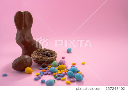 Chocolate Easter eggs and colorful sweets on a pink background. 137248402