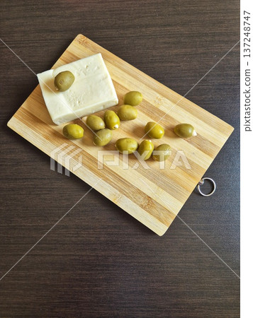 rich olives and salty white cheese (feta/brynza) on a wooden board rich olives and salty white cheese (feta/brynza) on a wooden board 137248747
