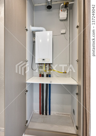 Gas boiler installed inside open utility cabinet 137249042