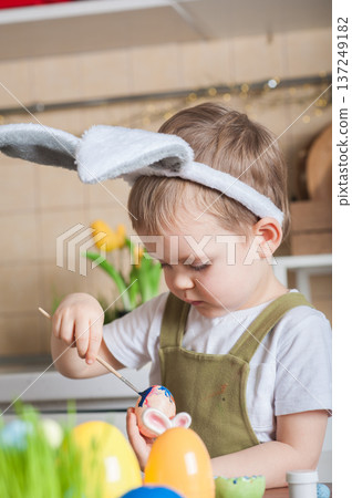 Toddler Painting Easter Eggs at Home in Festive Kitchen 137249182