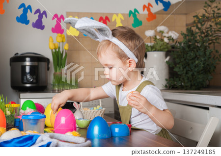 Toddler Painting Easter Eggs at Home in Festive Kitchen Toddler Painting Easter Eggs at Home in Festive Kitchen 137249185