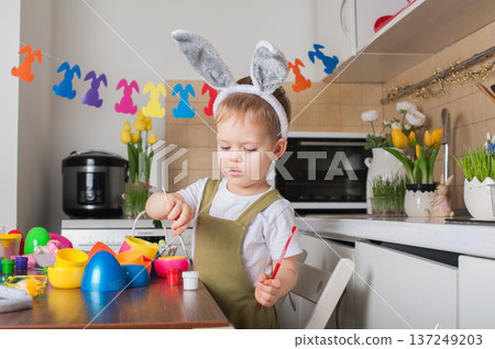 Toddler Painting Easter Eggs at Home in Festive Kitchen Toddler Painting Easter Eggs at Home in Festive Kitchen 137249203