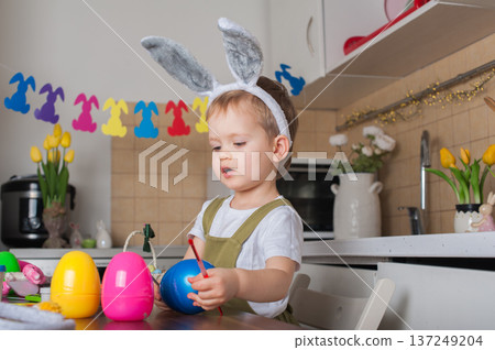 Toddler Painting Easter Eggs at Home in Festive Kitchen 137249204