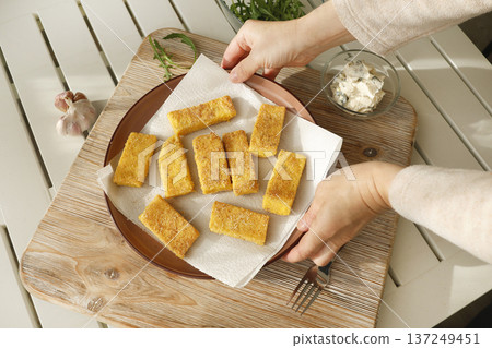 Sliced pieces of fried hard polenta on plate on table. Cornmeal in kitchen. Ingredients and traditional Italian cuisine. Sliced pieces of fried hard polenta on plate on table. Cornmeal in kitchen. Ingredients and traditional Italian cuisine. 137249451