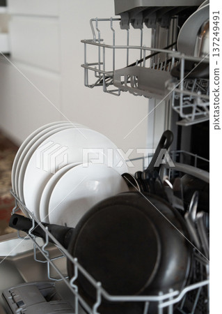 Dishwasher opening with freshly washed plates and pans, showing kitchen organization, hygiene, and domestic life convenience for modern households Dishwasher opening with freshly washed plates and pans, showing kitchen organization, hygiene, and domestic life convenience for modern households 137249491
