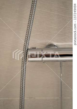 Chrome thermostat shower mixer with flexible hose, detail view of modern bathroom plumbing fixtures, close up of domestic water temperature control and supply 137249494