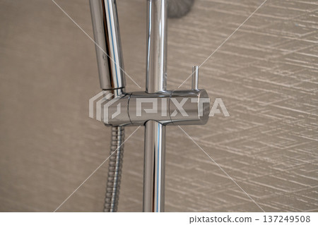 Modern bathroom shower fixture showing chrome hardware design, water hose, and adjustable holder for hygiene, daily routine, and wellness concepts Modern bathroom shower fixture showing chrome hardware design, water hose, and adjustable holder for hygiene, daily routine, and wellness concepts 137249508