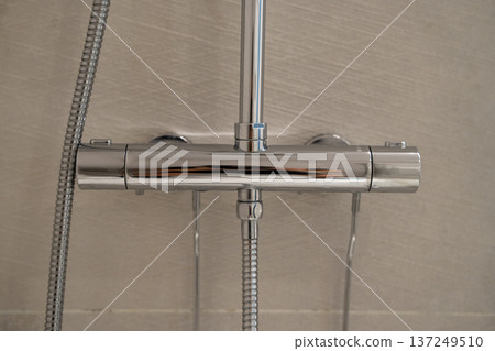 Modern chrome shower mixer faucet in bathroom, providing comfort and hygiene with adjustable water temperature on tiled wall Modern chrome shower mixer faucet in bathroom, providing comfort and hygiene with adjustable water temperature on tiled wall 137249510