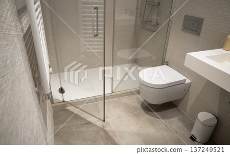 Creating a warm and inviting atmosphere in a bright, contemporary bathroom with a floating toilet, modern sink, glass shower, and white towel warmer Creating a warm and inviting atmosphere in a bright, contemporary bathroom with a floating toilet, modern sink, glass shower, and white towel warmer 137249521