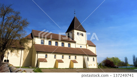 Historic church stands under clear blue sky in rural landscape during sunny day near quiet town 137249741