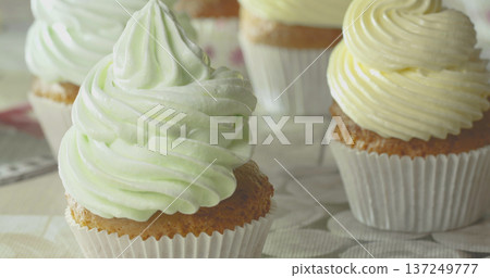 Cupcakes with green and yellow frosting sit on a table at a bakery during a sunny afternoon Cupcakes with green and yellow frosting sit on a table at a bakery during a sunny afternoon 137249777