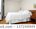 Hotel bedroom with white bed, pillows and quilt in neutral interior. Accommodation room with wooden furniture  137249949