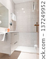 The interior of the hotel bathroom with beige tiled walls, a toilet and a mirror 137249952